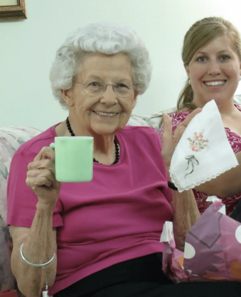 Stacy Jones and her grandmother on her 90th Birthday receiving an antique jadeite measuring cup and a vintage handkerchief