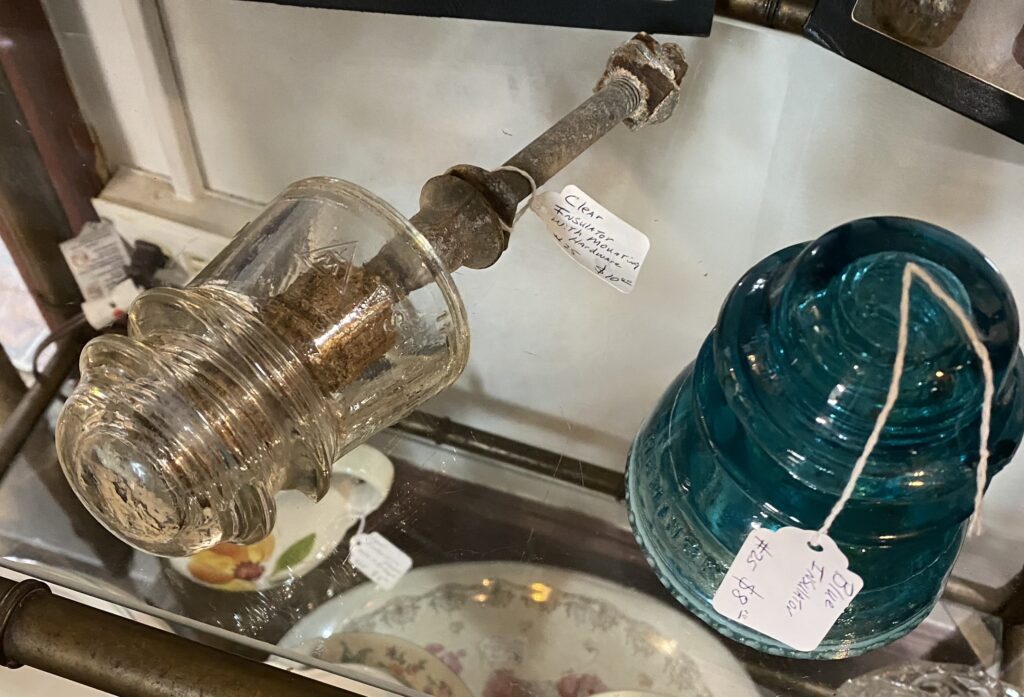 Left: clear vintage glass insulator with mounting hardware. Right: blue Hemingray vintage glass insulator